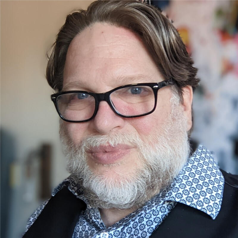 Chris Brogan headshot. He has short hair, wearing glasses and a white shirt with a small blue floral pattern.